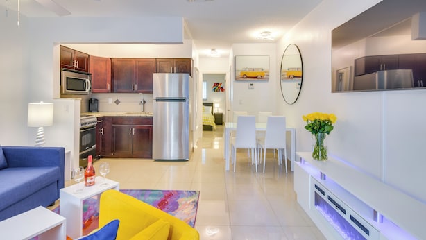 A modern living room with a sofa, a coffee table, and a dining area with chairs and a table. - Your Ideal 30-Day Furnished Retreat in Hallandale! (Hallandale Beach)