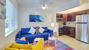 A modern living room with a blue sofa, yellow armchair, and a colorful rug. - Your Ideal 30-Day Furnished Retreat in Hallandale! (Hallandale Beach)