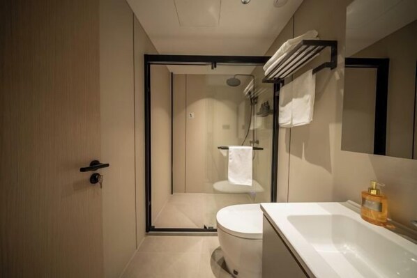 A modern bathroom with a glass-enclosed shower, a toilet, and a sink with a mirror.