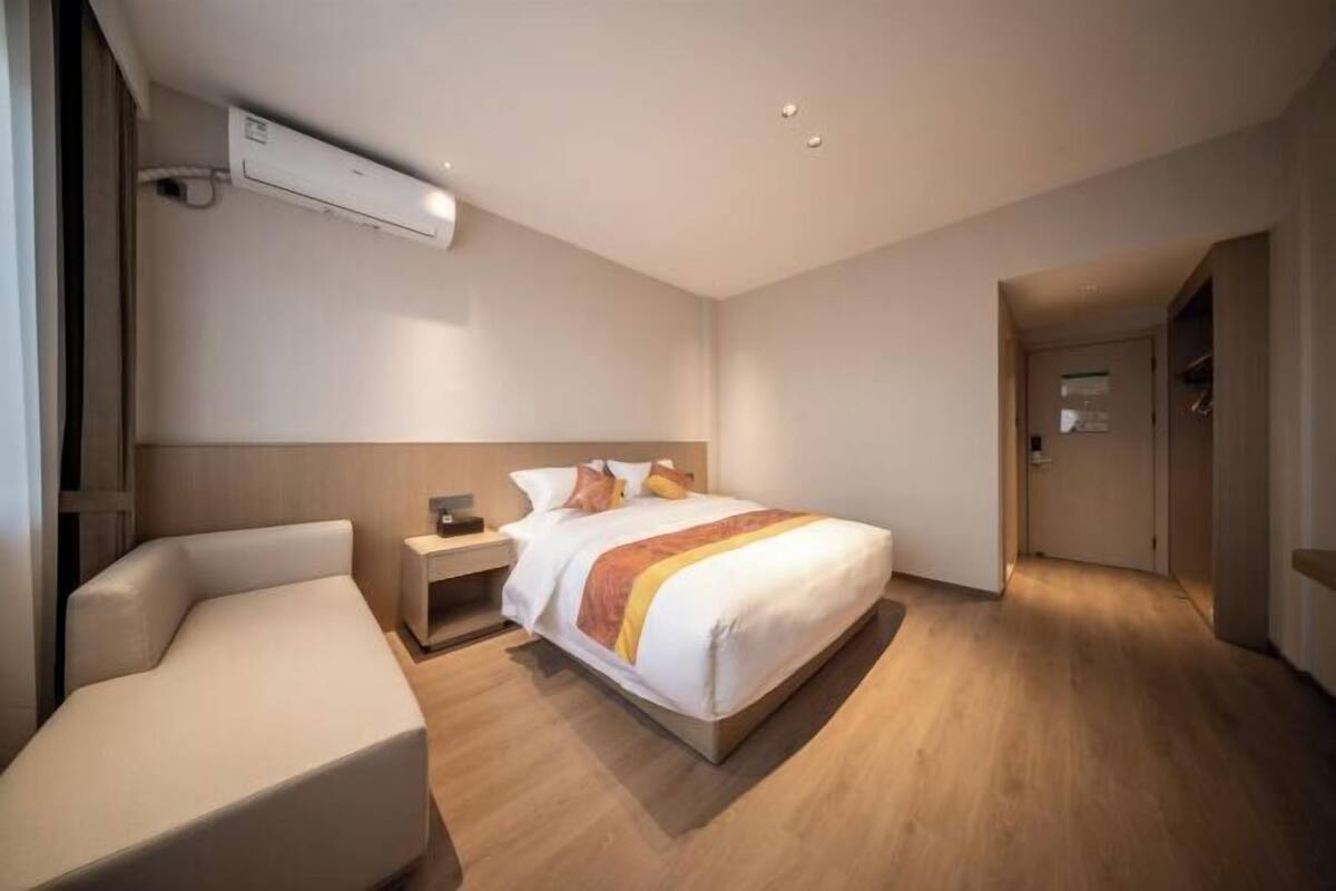 A modern hotel room with a bed, bedside table, and a seating area.
