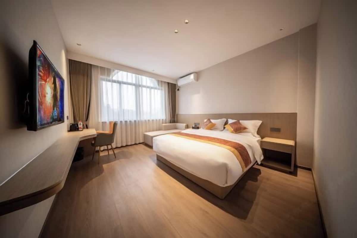 A modern hotel room with a large bed, a desk, and a TV mounted on the wall.