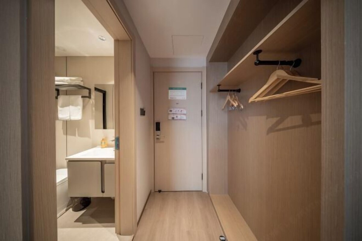 A narrow hallway leading to a bathroom with a sink and towel rack.