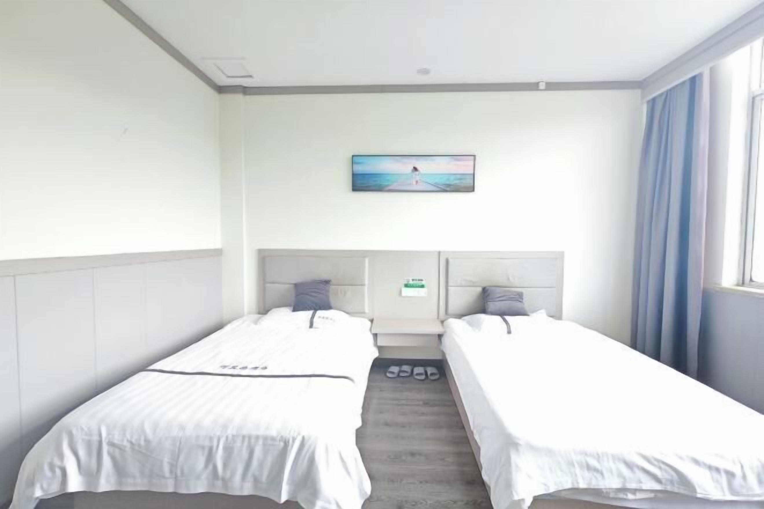 A hotel room with two single beds, a painting on the wall, and a window with curtains.