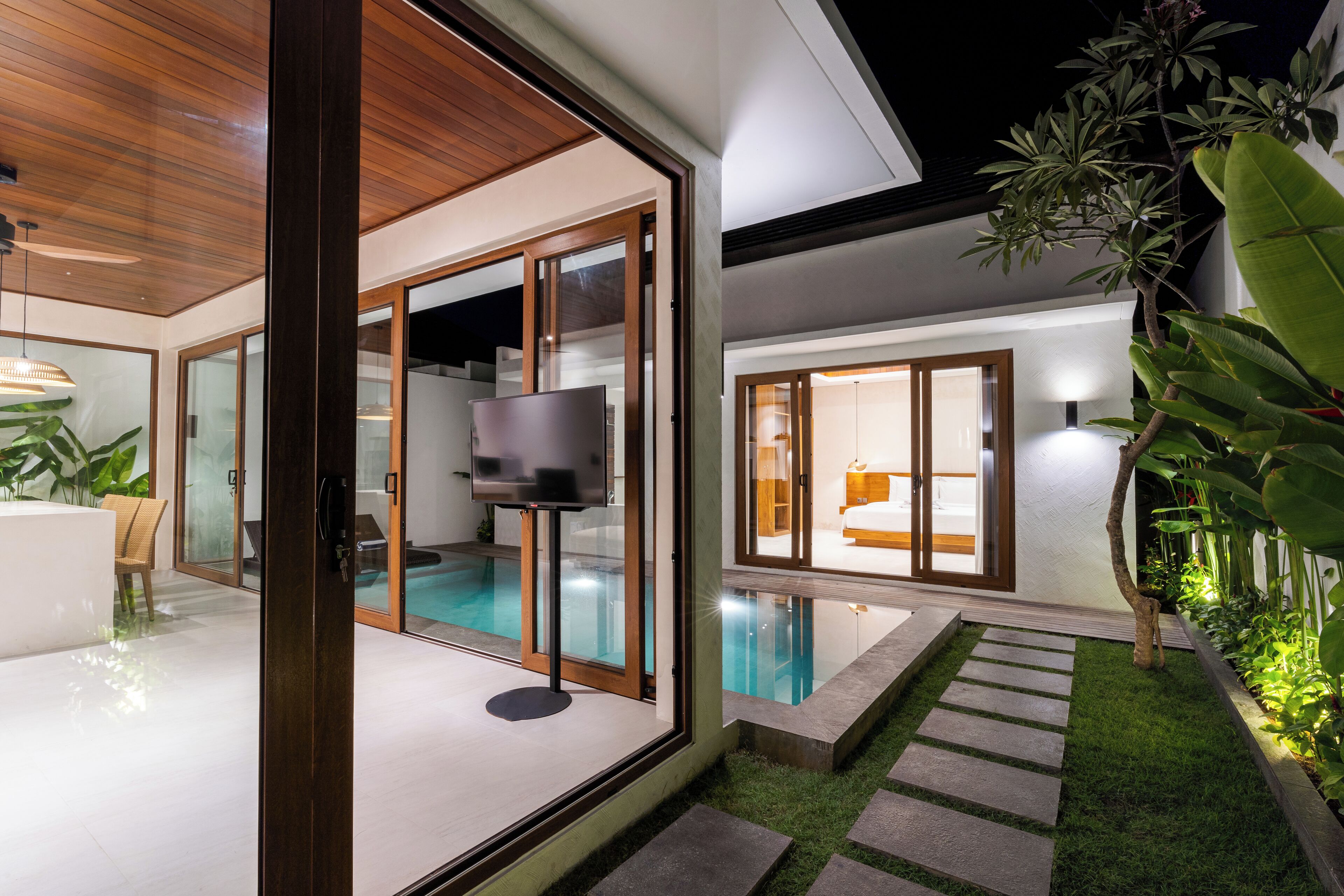 Uma casa moderna com piscina, amplas portas de vidro e interior bem iluminado.