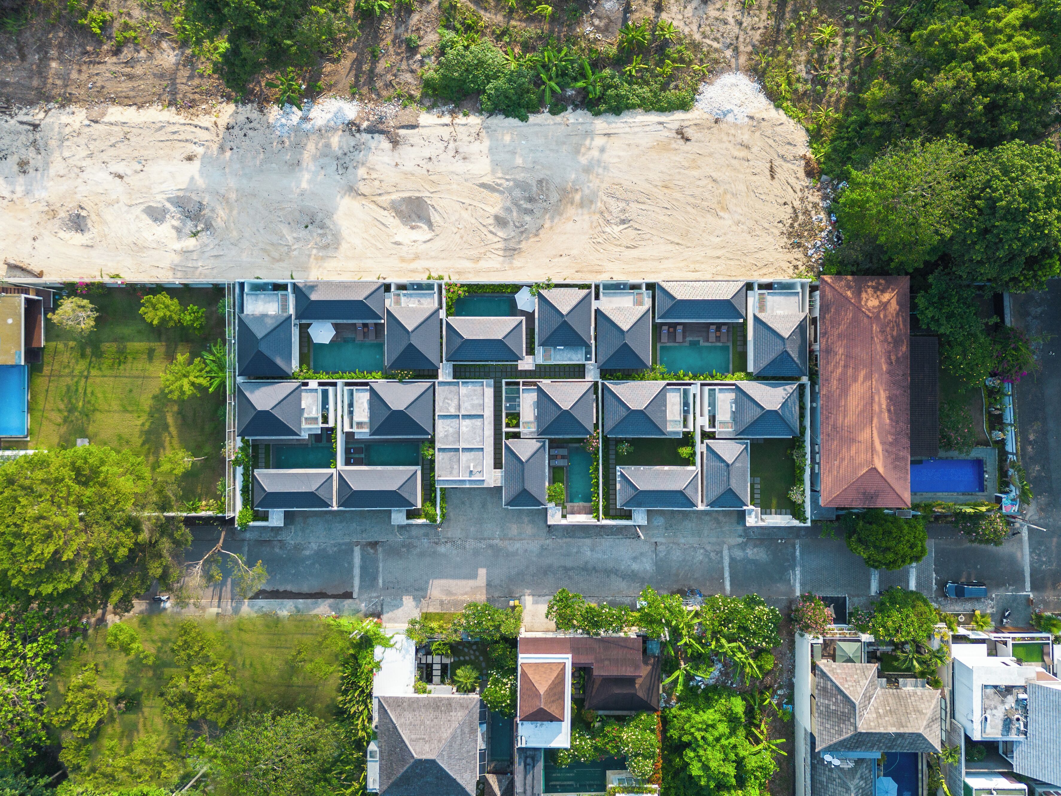 Vista aérea de um hotel moderno com vários quartos, piscina e área de praia.