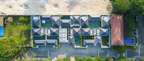 Vista aérea de um hotel moderno com vários quartos, piscina e área de praia.