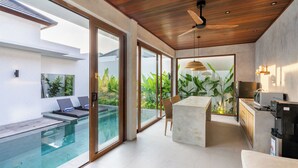A modern interior with a glass-enclosed pool, a wooden ceiling, and a kitchen area. - J4 Villas Sanur (Denpasar)