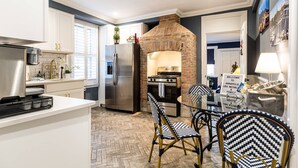 A modern kitchen with a built-in brick oven, stainless steel appliances, and a herringbone-patterned floor.