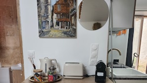 Eine moderne Küche mit Holztischplatte, einem Toaster, einem Wasserkocher und einem Gemälde einer europäischen Straßenszene.