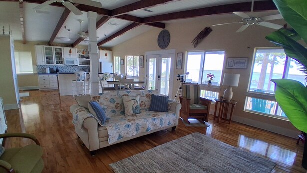 A spacious living room with a sofa, a dining area, and a kitchen in the background.