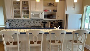 A kitchen with a central island, white cabinetry, and a wooden floor. - Ochlocknee Bay Waterfront King Suite Private Dock Top Floor (Panacea)