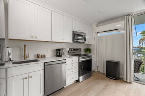 A modern kitchen with white cabinetry, stainless steel appliances, and a view to the outside. - Waterfront w/Pool! FREE Activities! ~ 22 Bayside (Clearwater)