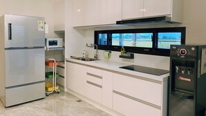 A modern kitchen with white cabinets, a built-in microwave, a stainless steel refrigerator, a black range hood, and a water dispenser. - 58mutian B&B (Zhuangwei)
