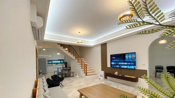 A modern living room with a sofa, a coffee table, a TV, and a staircase leading to a kitchen. - 58mutian B&B (Zhuangwei)