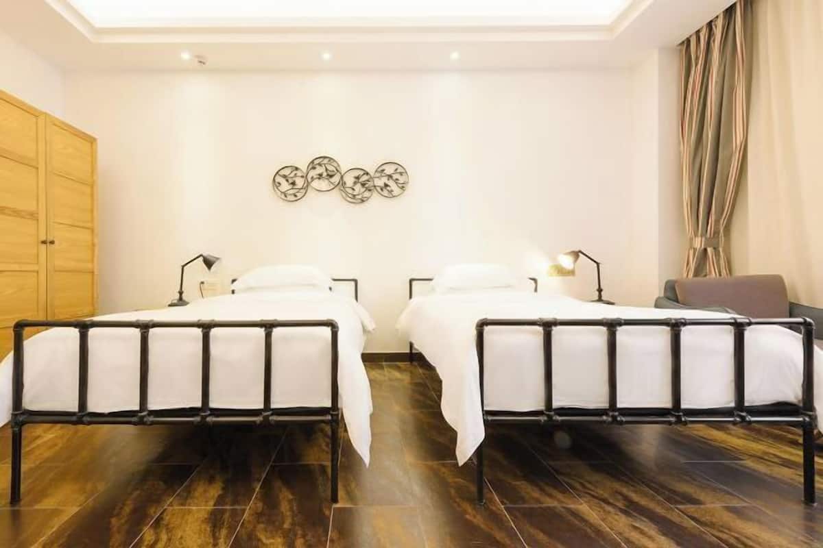 Une chambre avec deux lits, une armoire et un luminaire fixé au mur.