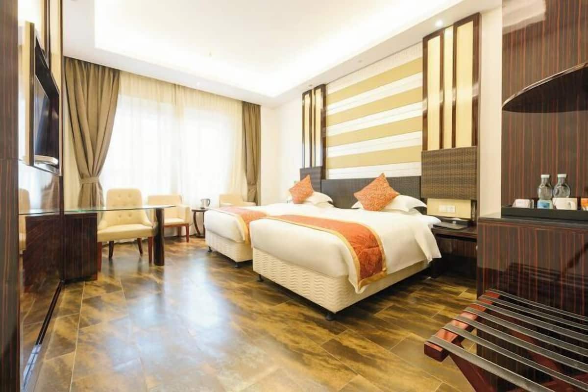 Une chambre d’hôtel avec deux lits, une télévision, un bureau et un coin salon.