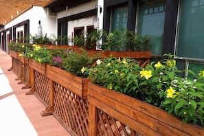 A row of wooden planters with various plants and flowers along a building's exterior. - Heyuan Boutique Hotel (Dongyuan)