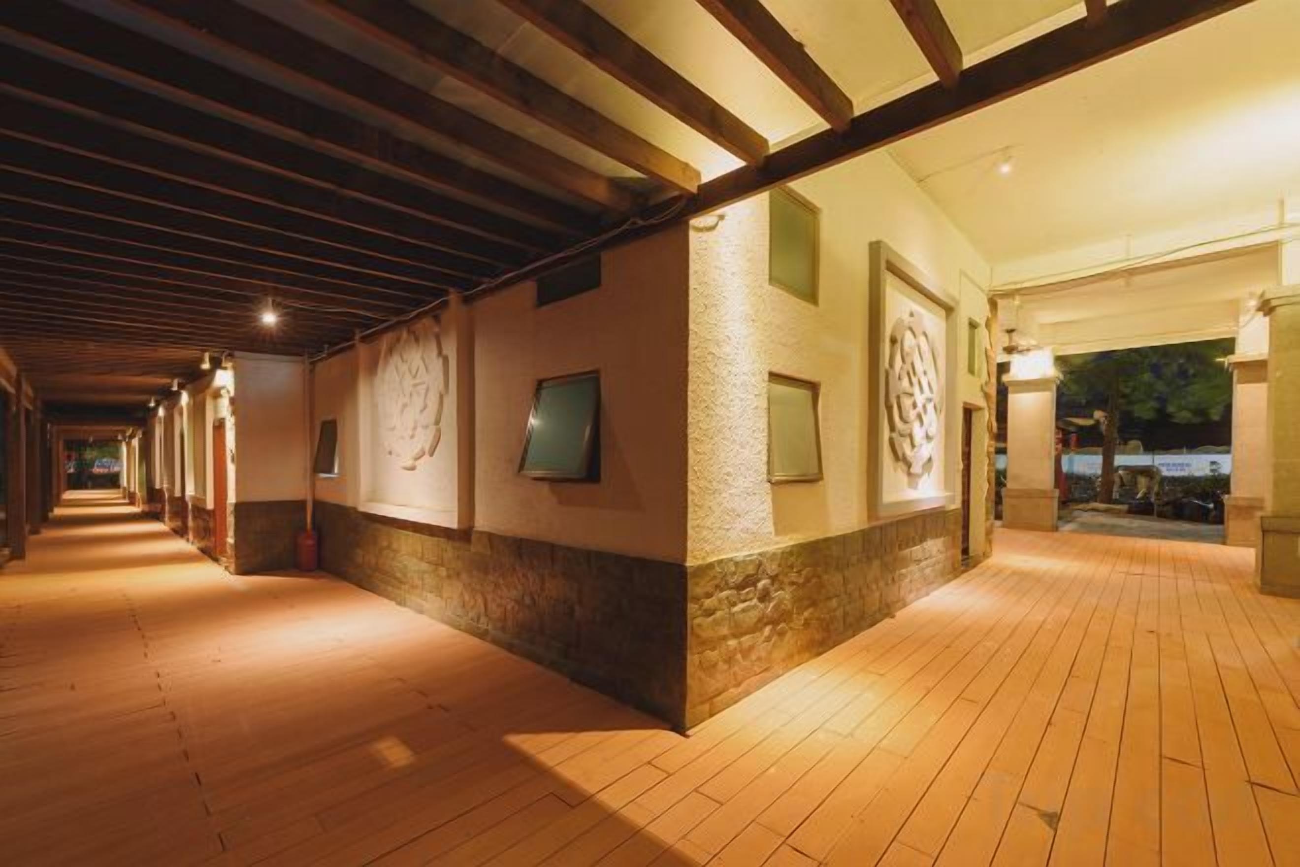 A corridor with wooden flooring, stone walls, and framed artwork.