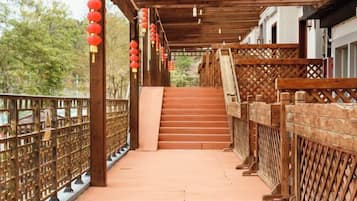 A wooden staircase leading to a covered area with a tiled floor and a wooden railing.