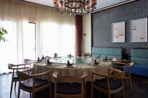 A dining area with a round table, chairs, and a glass-top table. - Heyuan Boutique Hotel (Dongyuan)