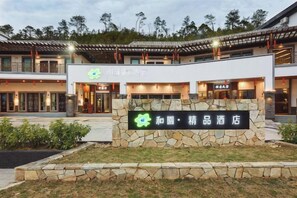 Un hotel de estilo arquitectónico tradicional, con fachada de piedra y cartel con el nombre del hotel.