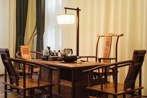 A traditional wooden dining table with four chairs, a floor lamp, and a decorative bowl on the table.