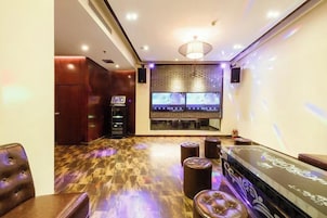 A room with a bar area, seating, and a television screen.