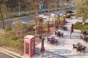 Un patio con mobiliario exterior, una cabina telefónica roja y una carretera al fondo.