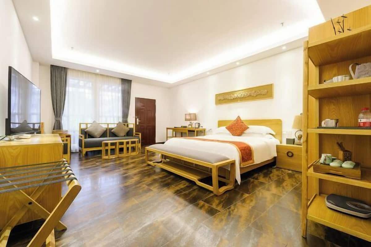 Une chambre d’hôtel avec un lit en bois, un bureau, une chaise, une télévision et une bibliothèque.