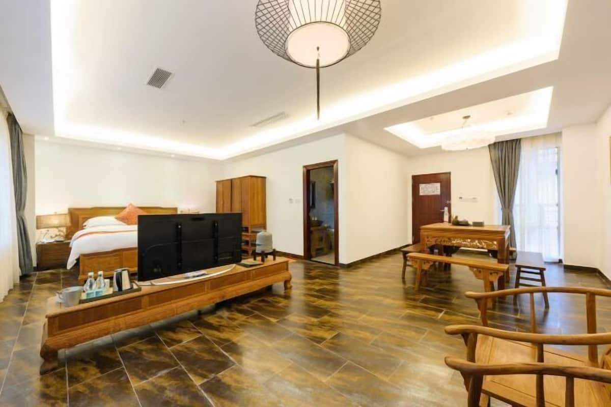 Une chambre d’hôtel avec un lit, une télévision, des meubles en bois et un coin repas.