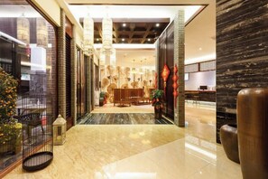 A hotel lobby with a reception desk, seating area, and a decorative wall.