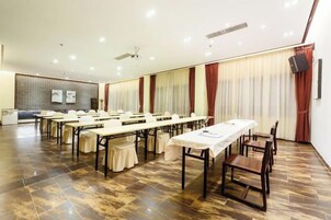 A conference room with multiple tables and chairs, a whiteboard, and a projector screen.