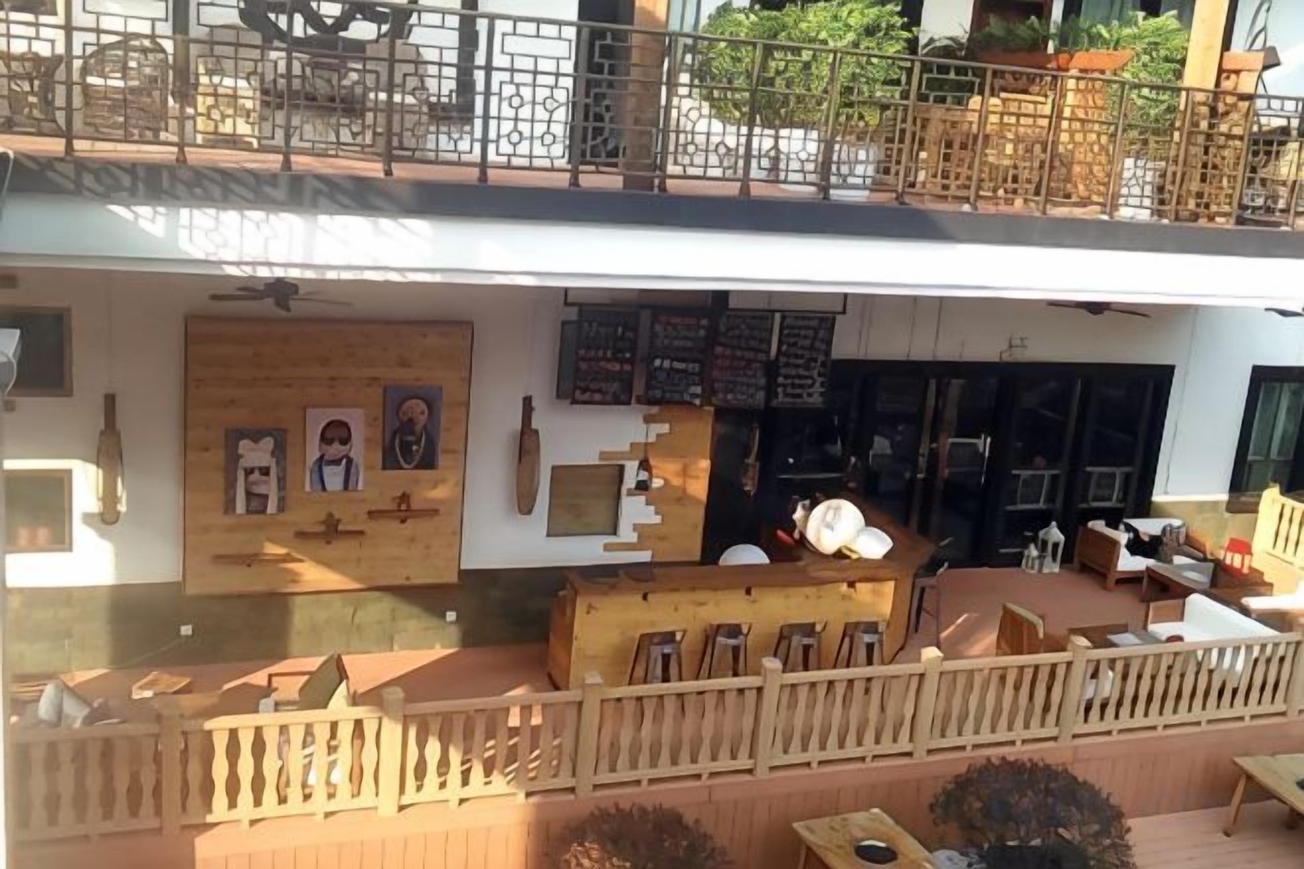 A restaurant with outdoor seating, a wooden facade, and a balcony.