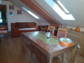 Une pièce mansardée comprenant une table à manger, un canapé et un coin cuisine.