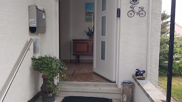 Unos escalones de hormigón conducen a una puerta, donde se observa un buzón y un símbolo de bicicleta en la pared.