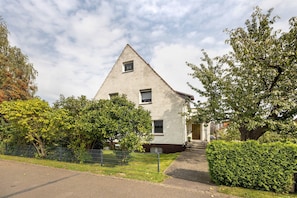 A residential building with a triangular roof, a small window, and a door.