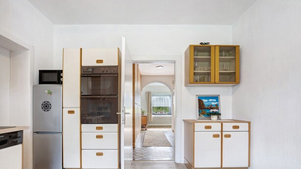 A kitchen with a refrigerator, oven, microwave, and wooden cabinets.