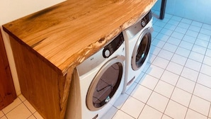 Ein Waschbereich mit Holztischplatte, zwei Waschmaschinen und einem Waschbecken.