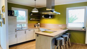 Een moderne keuken met een centraal eiland, barstoelen, een magnetron, een koffiezetapparaat en een raam.
