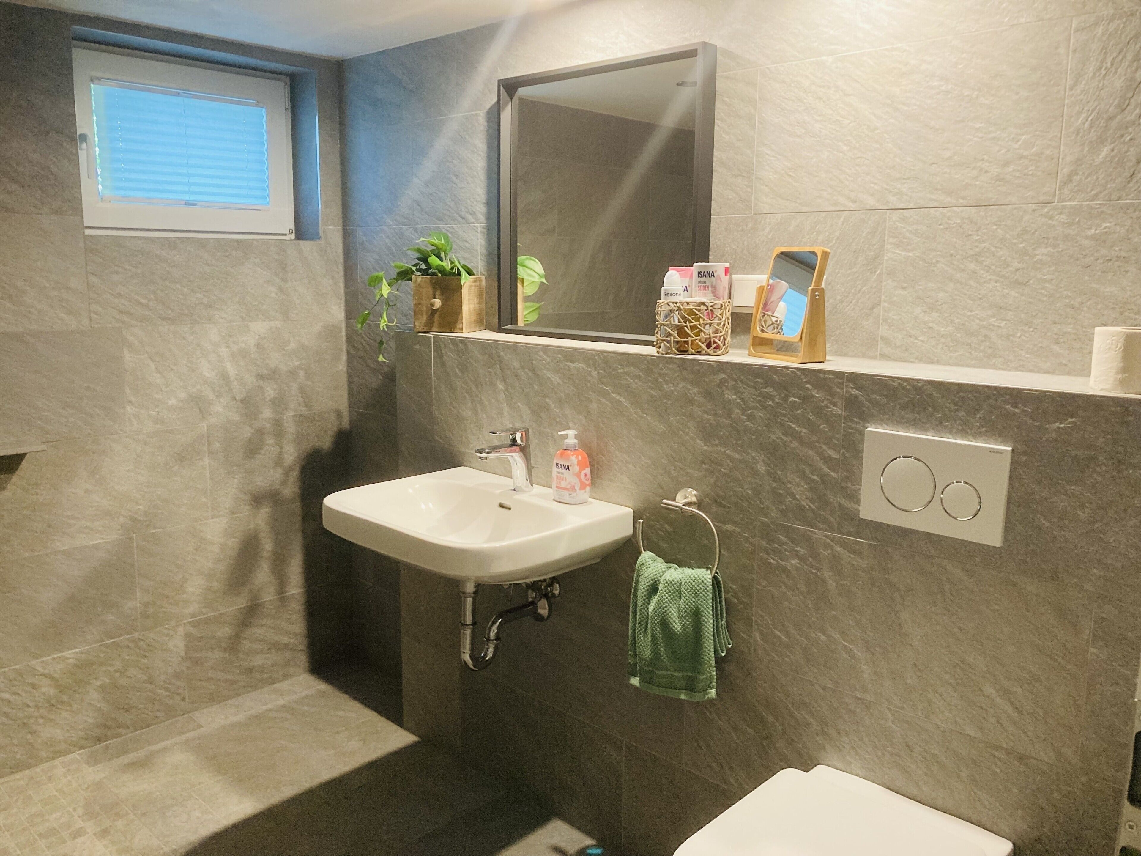 A bathroom with a sink, mirror, towel rack, and a window with blinds.
