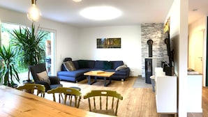 Een moderne woonkamer met een bank, eettafel, stoelen en een open haard.