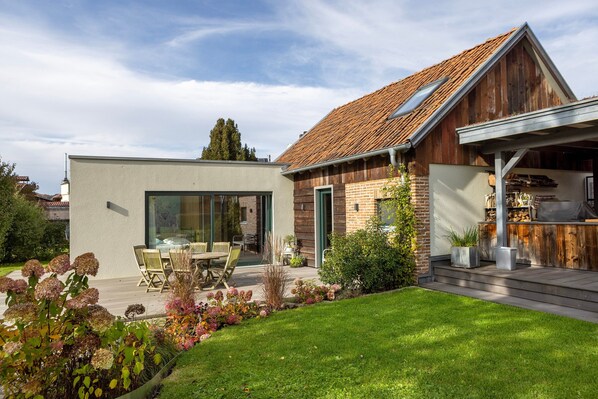 Et moderne hus med en patio, spiseplads og en træterrasse.
