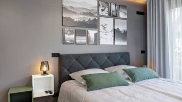 Una camera da letto con un letto, un comodino, una lampada e una parete con quadri.