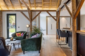 Ein modernes Interieur mit Holzboden, einem grünen Sofa, einem Essbereich und einem großen Fenster.