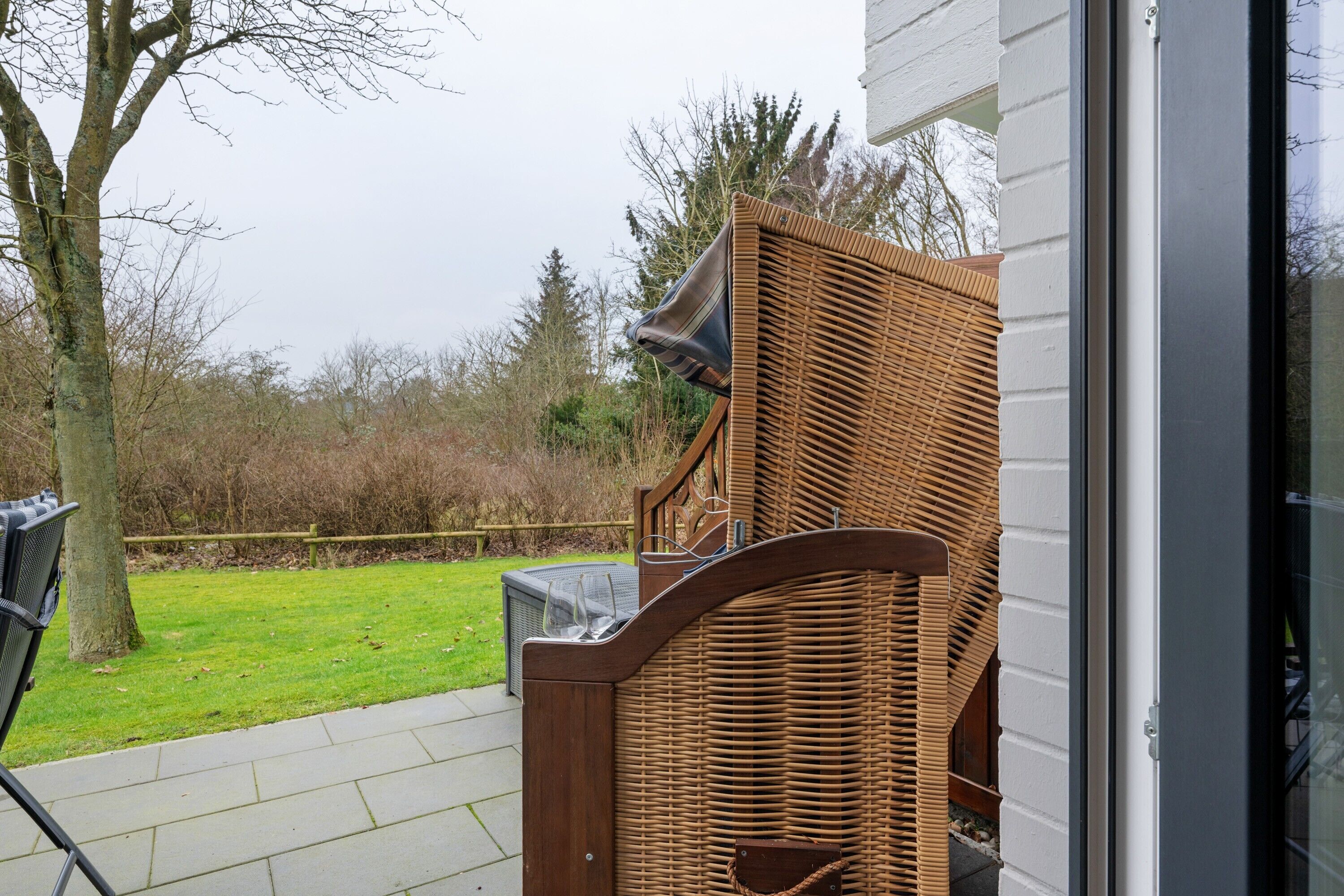En fletstol, en glasbeholder og en metalstol foran en bygning.