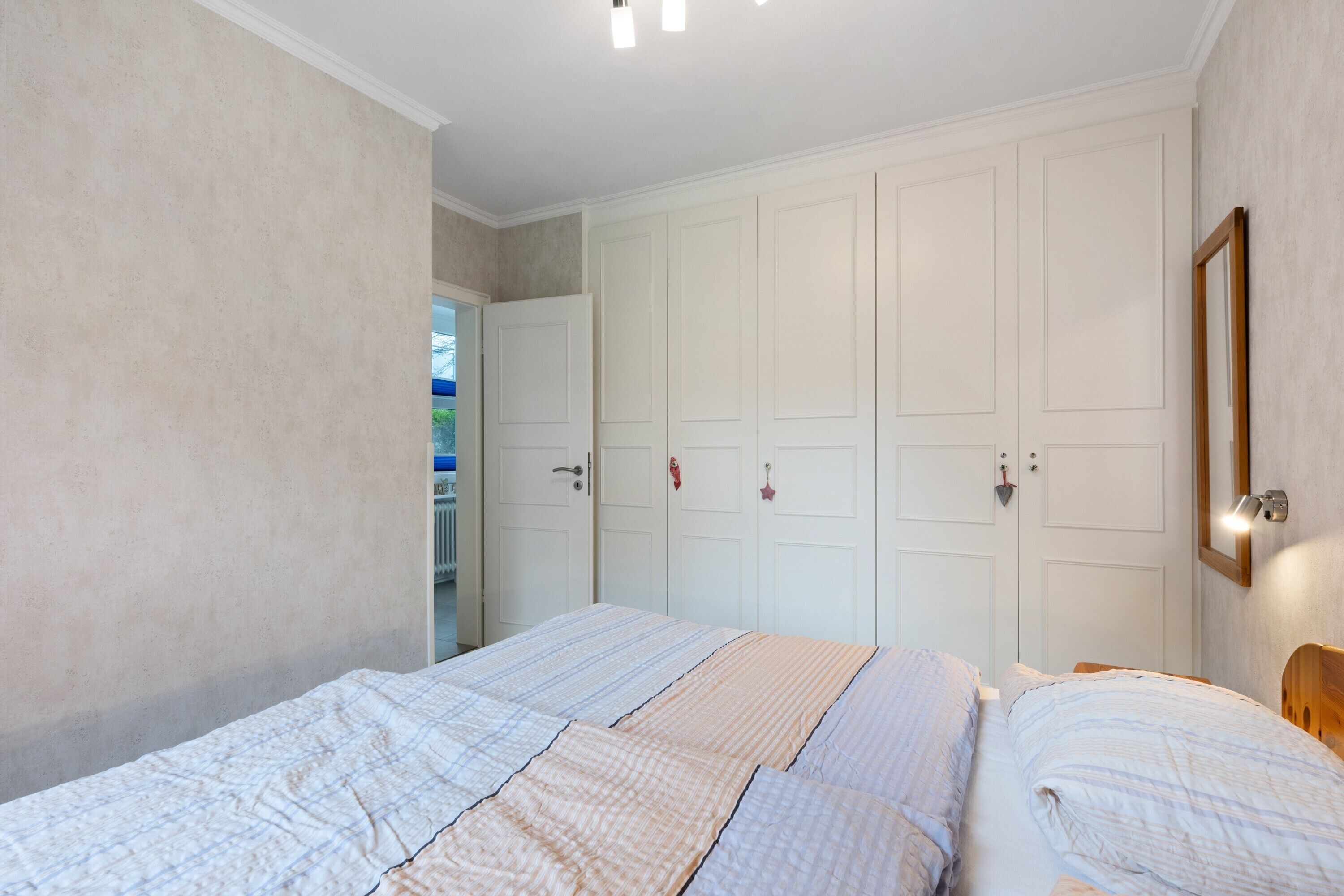 Ein Schlafzimmer mit Bett, Kleiderschrank und Spiegel.