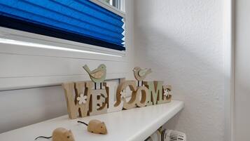 Ein weißes Regal mit einem 'WELCOME'-Schild, zwei Holzfiguren von Vögeln und zwei kleine Tierfiguren.