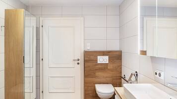 Un baño moderno con tocador de madera, inodoro blanco y espejo grande.