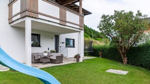 Une maison moderne dotée d’un patio couvert, d’un toboggan bleu et d’une pelouse bien entretenue.