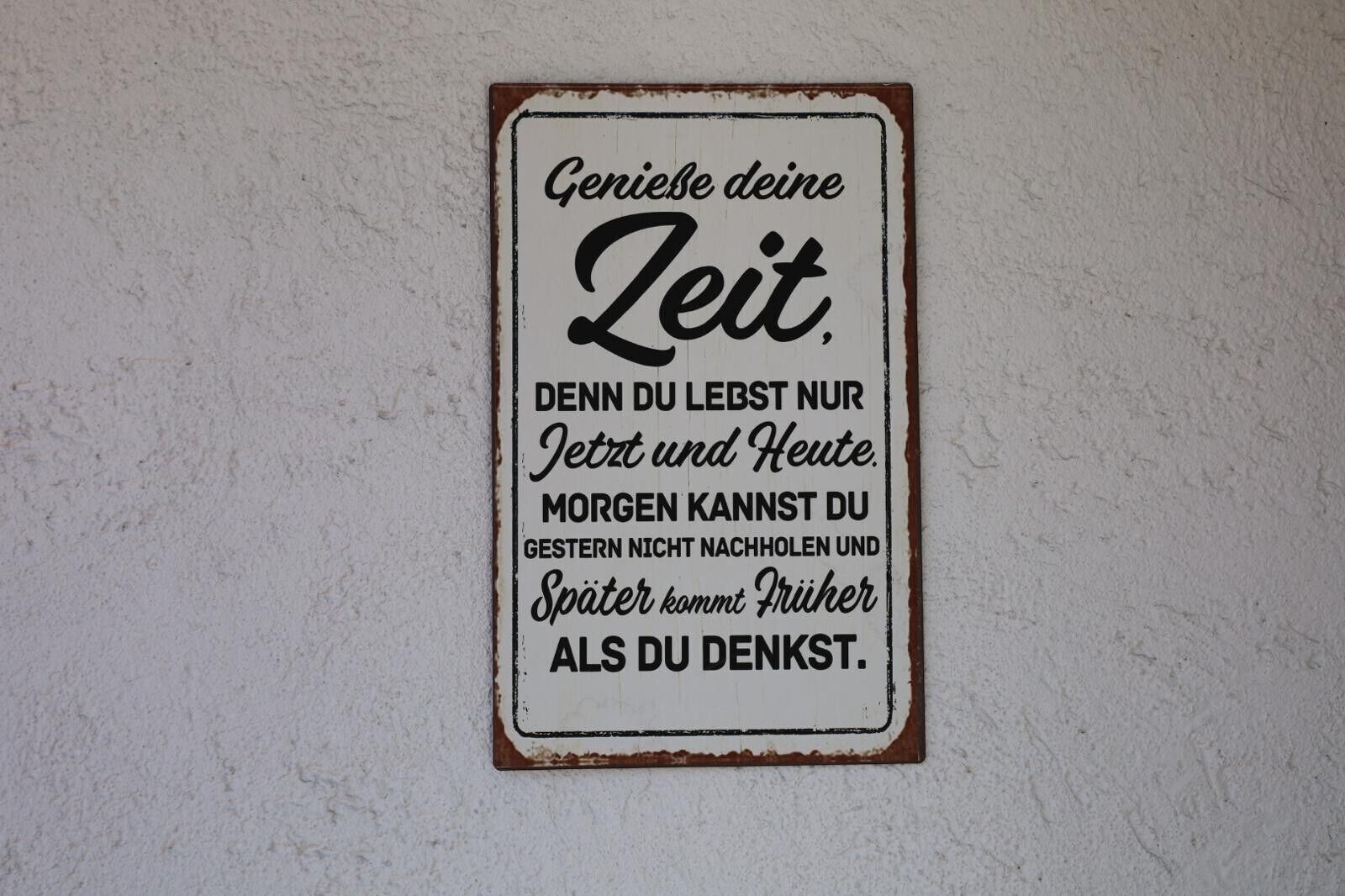 Ein Schild mit deutschem Text an einer strukturierten Wand.